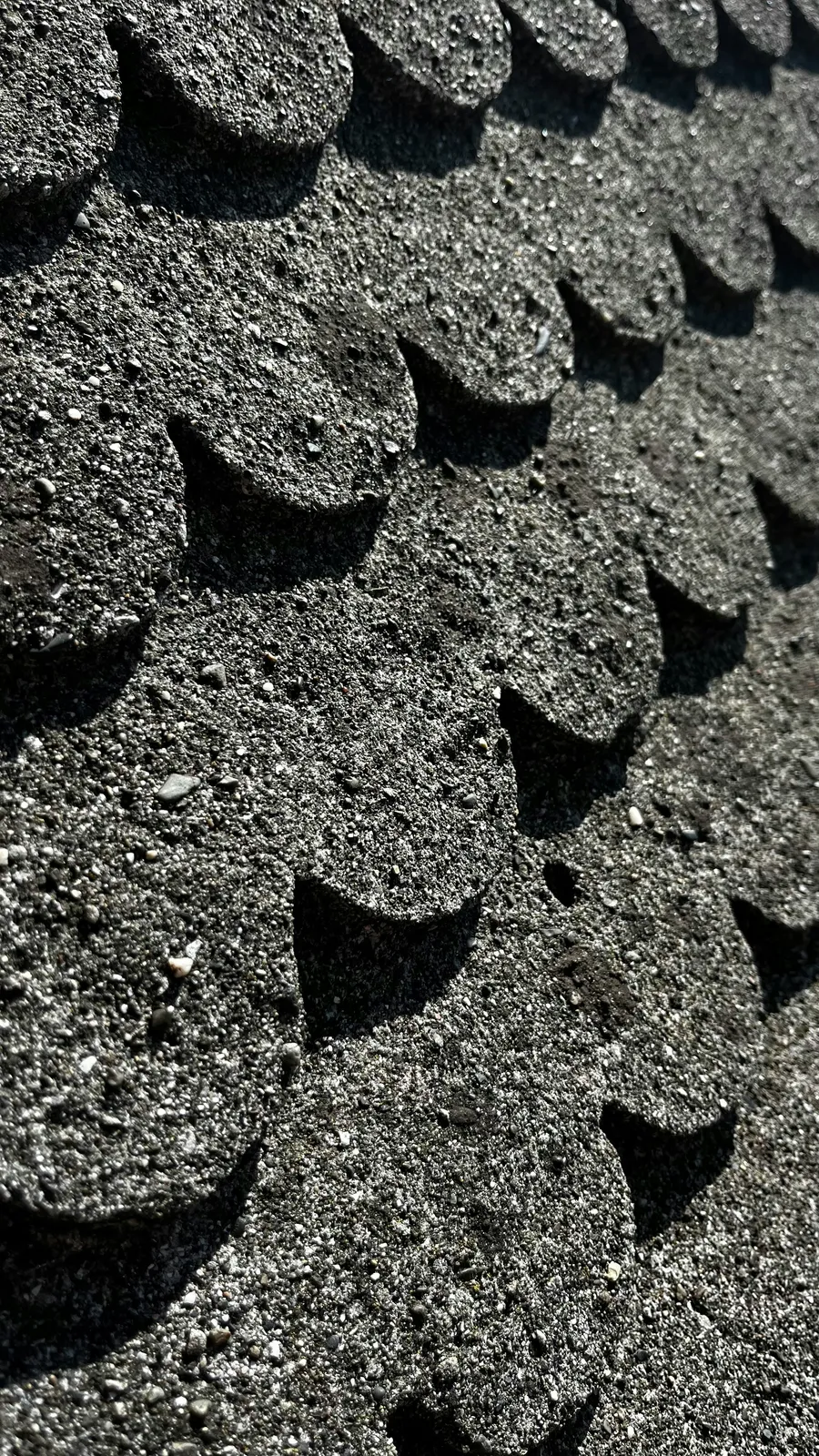 Extreme close-up of black scalloped shingle edges and mineral granules